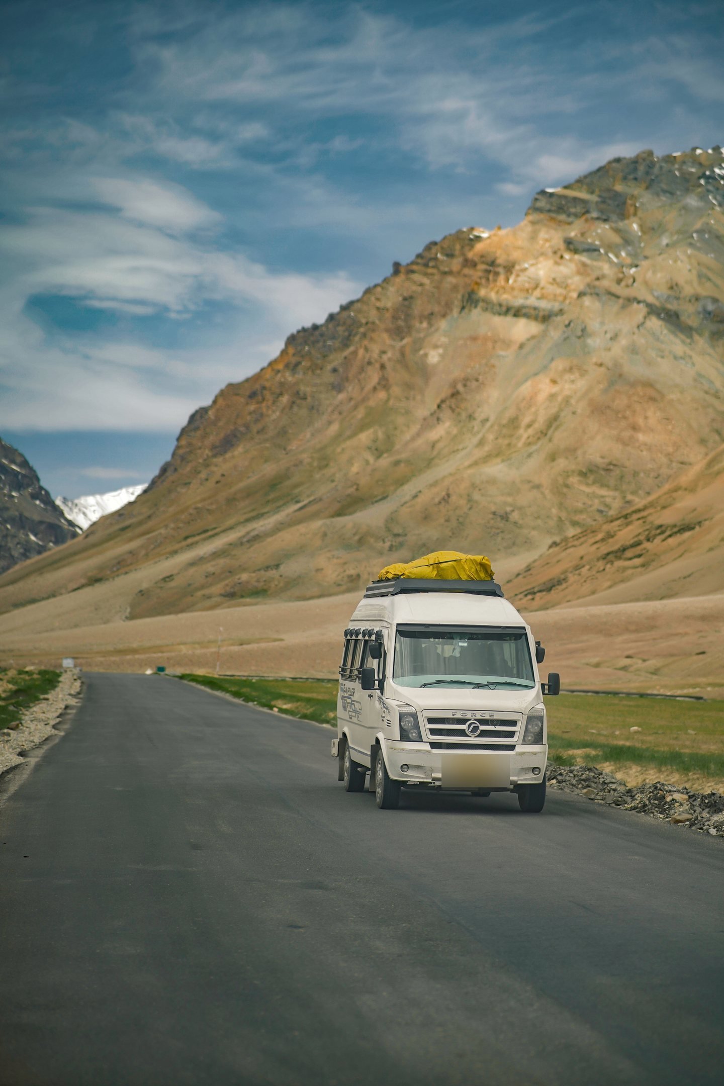 White Force Traveller van on a mountain road, luggage on the roof rack